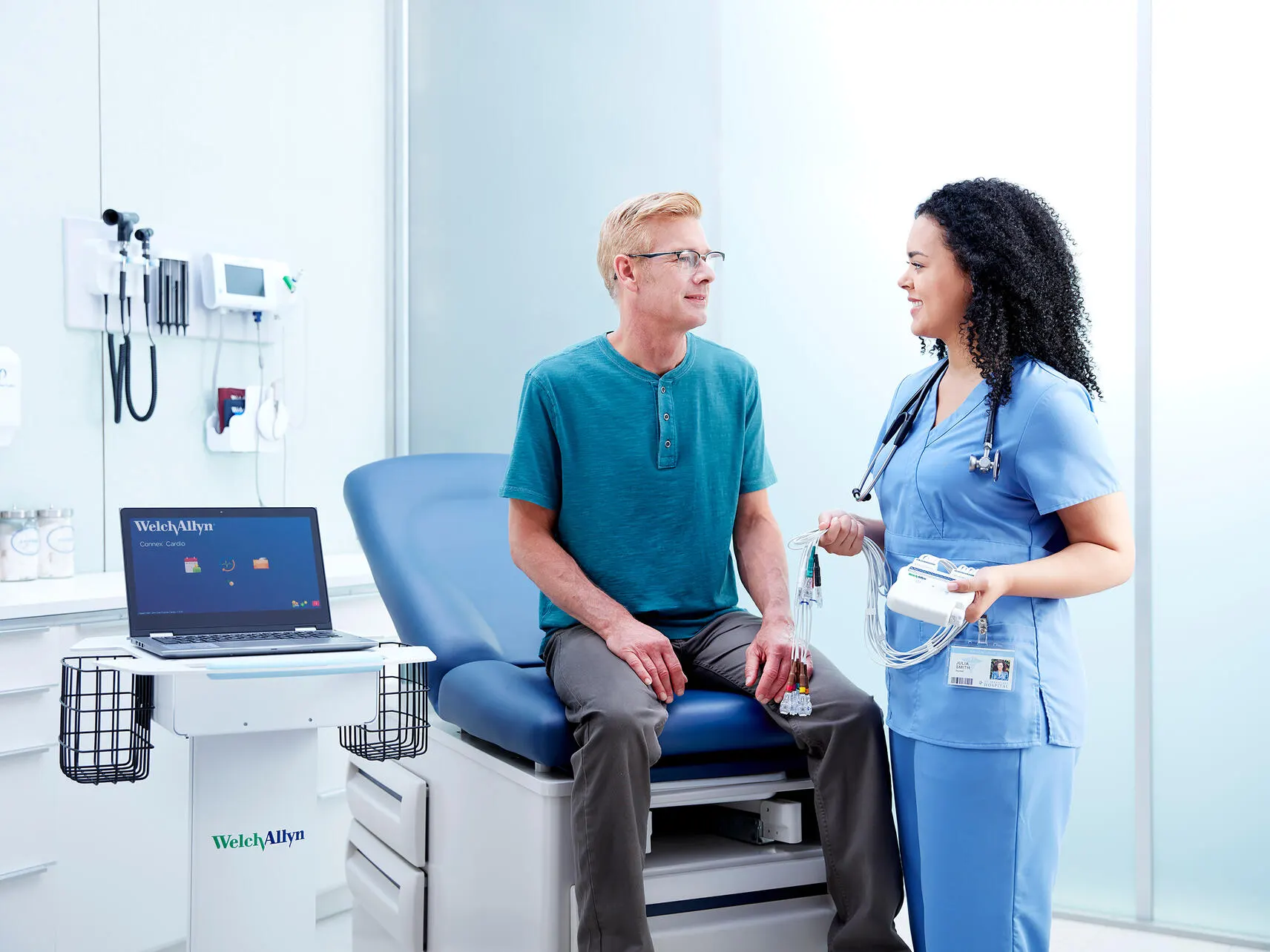 Cardiology technician holding electrodes next to a patient in an outpatient office